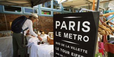A man in a white hat peruses a stall marked 'Paris Le Metro' at the French Market at Killarney Heights Public School.