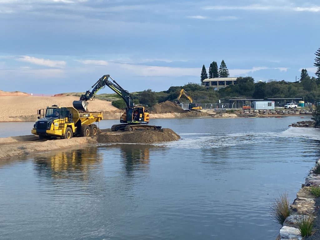 A digger and truck work on Narrabeen Lagoon clearance works